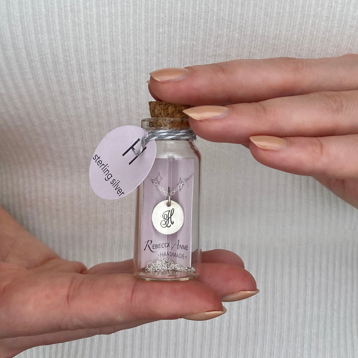 Sterling silver initial necklace displayed in signature glass bottle packaging