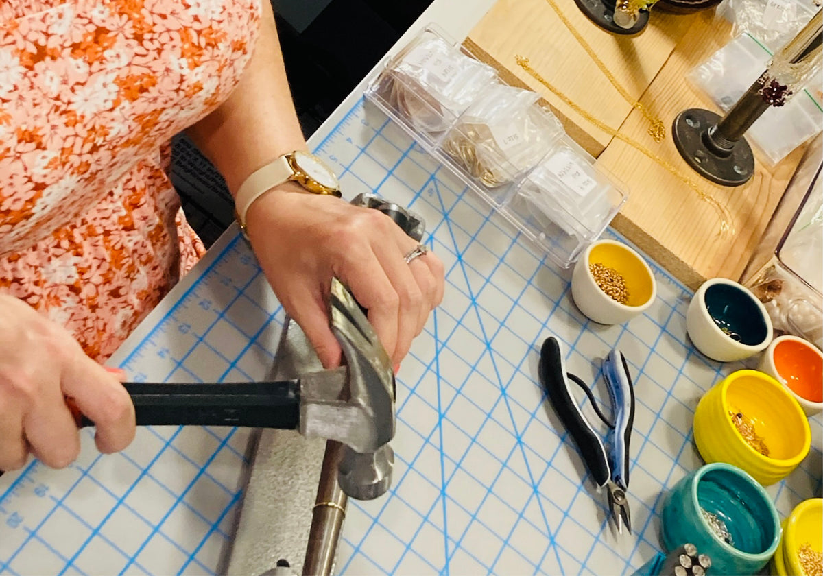 Rebecca hand hammering jewelry at her workbench